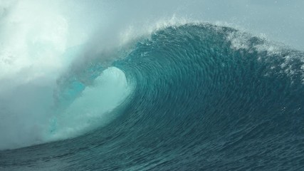 Wall Mural - SLOW MOTION, CLOSE UP: Glimmering barrel wave rushes past the camera on a sunny day in Tahiti. Big tube wave sprays sparkling drops of ocean water high in air while it approaches a remote island.