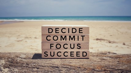 Wall Mural - Motivational and inspirational quote - ‘ Decide, commit, focus, succeed’ on a wooden blocks. With vintage styled background.