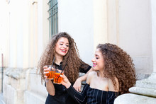 Fashion Blogger Twins Toasting With Cocktail By Building