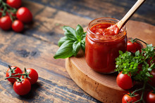 Tomato Sauce In A Glass Jar, Tomatoes And Herbs On Its Side.