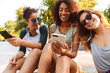 © Drobot Dean - Three friends woman using mobile phones listening music with earphones.