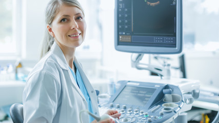 Wall Mural - In the Hospital, Professional Female Obstetricians Smiles on Camera at Her Working Place.