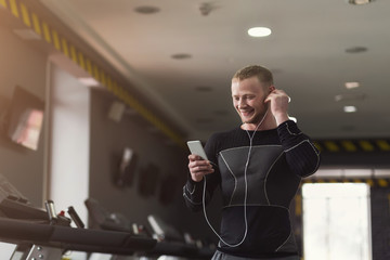 Wall Mural - Young sporty man on treadmill in fitness club