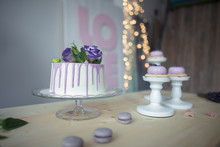 White Sponge Cake With Purple Decoration On A Wooden Table