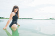 © phpetrunina14 - woman walking in blue water in black swimming suit