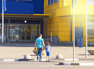 Dad and son going shopping in the supermarket. They are at an entrance to a mega shopping center.