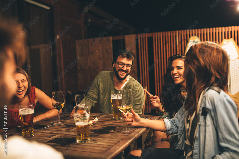 Group of friends drink beer on the terrace during summer night - obrazy, fototapety, plakaty 