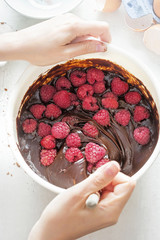 Wall Mural - Female hands mixing raspberries with chocolate brownies batter in white bowl