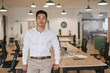 © mavoimages - Confident Asian businessman leaning on a desk in an office