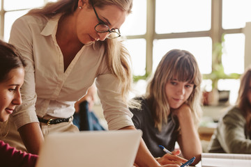 Wall Mural - Female lecturer helping student during her class