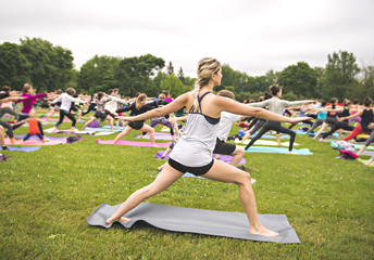 Wall Mural - big group of adults attending a yoga class outside in park