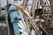 Old blue antique iron water pump and large white cartwheel with vintage wooden ladders in background