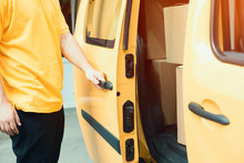 Man Closes Slide Van Door. Cropped Picture Of Delivery Man Wearing Yellow Shirt Closing Door Of Yellow Mini Van.