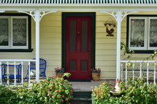 Romantic Porch Of Vintage Wooden House With Red Door In Dark Green Frame.