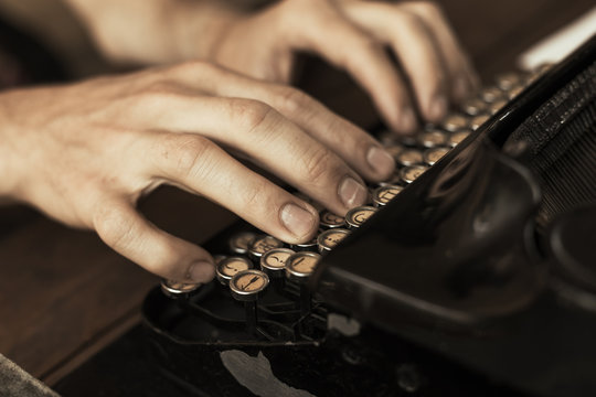 Young man's hands typing on an antique vintage typewriter