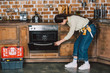 © LIGHTFIELD STUDIOS - confident young repairwoman examining oven at kitchen