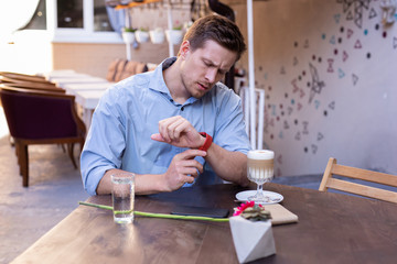 wrist watch. handsome good-looking stylish man looking at his nice red wrist watch while running lat