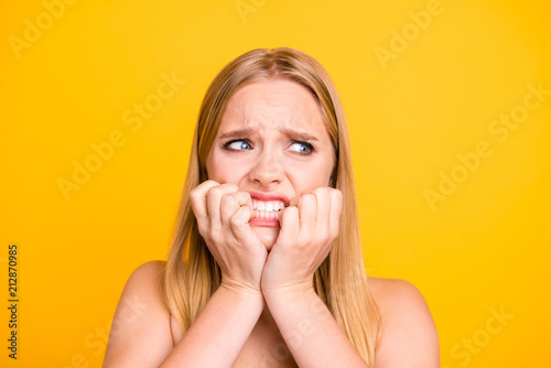 Fotomural Woman with nervous expressions face, keeps hands near mouth and stare with big eyes against yellow background