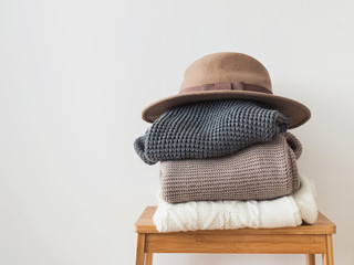 Stack of warm knitted sweater and felt hat on the top of it