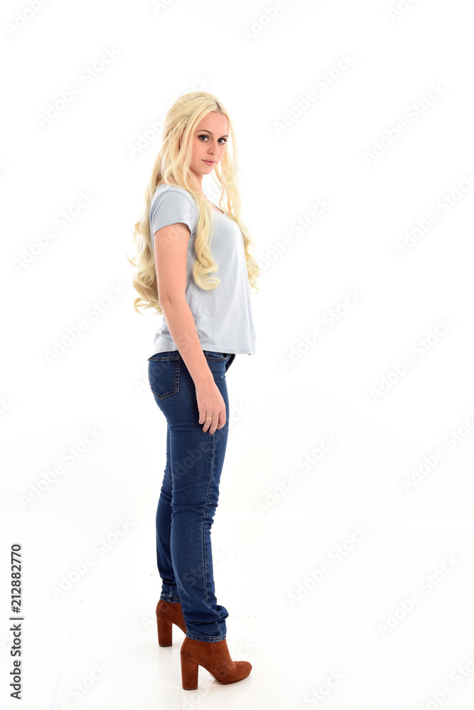 full length portrait of blonde girl wearing simple blue shirt and jeans ...