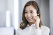 © Blue Jean Images - Cheerful young Chinese businesswoman with headset in office