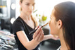 selective focus of woman getting makeup done by makeup artist