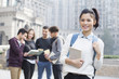 © Blue Jean Images - Cheerful female abroad student on campus with her friends in background