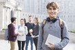 © Blue Jean Images - Cheerful male abroad student on campus with his friends in background