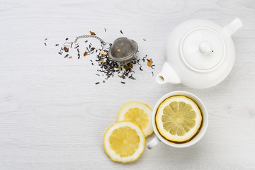 Poster - cup of tea with lemon slices, teapot and infuser on table