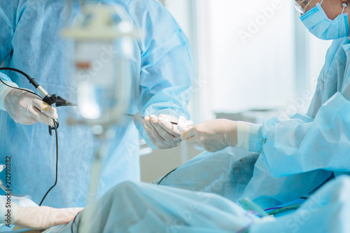 Fotomural Close up of hands of surgeons team during operation uterus removal with surgical laparoscopy instruments