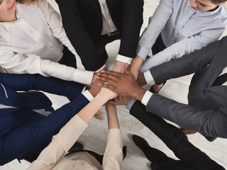 Team of united coworkers standing with hands together