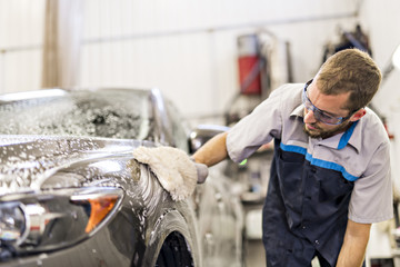 Man at work cleaning automobile at car wash