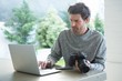 © Wavebreak Media - Man using laptop and holding digital camera