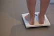 © Wavebreak Media - Woman checking her weight on weighing scales at home
