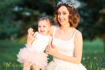 Mom and daughter are two years old sitting on the grass