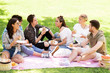 © Syda Productions - friendship, leisure and fast food concept - group of happy friends eating sandwiches or burgers at picnic in summer park