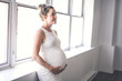 © Louis-Photo - pregnant woman with belly at home close to a window