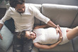 © Louis-Photo - Young happy Couple expecting baby on sofa