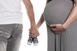 © Louis-Photo - Pregnant woman and man holding baby shoes