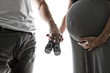 © Louis-Photo - Pregnant woman and man holding baby shoes