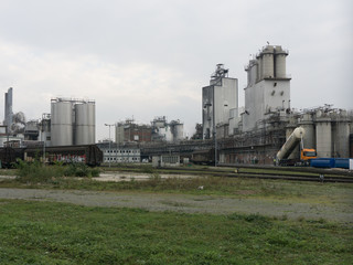 Wall Mural - Large chemical factory in gray in cloudy weather with railway station