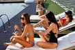 © djile - Four young women in a penthouse on sun chairs near the pool  have fun