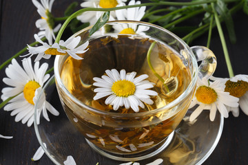 cup of herbal chamomile tea with fresh daisy flowers on wooden background. doctor treatment and prevention of immune concept