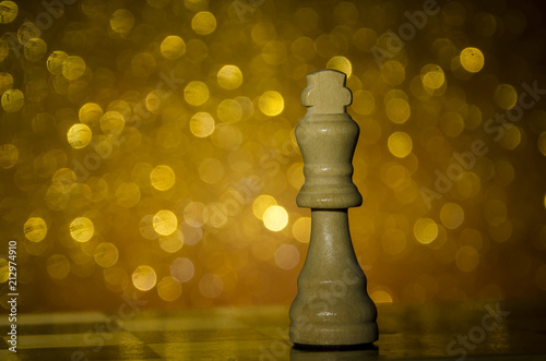 Fotografía Pieza de ajedrez en fondo dorado brillante. Rey de madera.