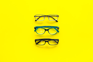 Wall Mural - Glasses concept. Set of glasses with different eyeglass frame and transparent lenses on yellow background top view copy space pattern