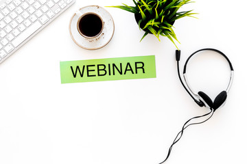 Poster - Professional training online. Word webinar on white office work desk with computer keyboard, headphones, plant and coffee top view copy space