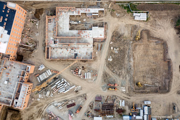 Aerial view:Construction of residential multi-storey houses with the help of a construction crane, excavator loading the tipper truck   in a new residential area of the city.