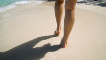 Following Girl Walking Along White Sandy Beach Through Waves On Beautiful Tropical Island.