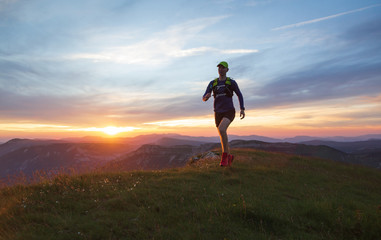 Wall Mural - Athlete trail running in Massif du Vercors during sunset. Shallow D.O.F. and with motion blur.