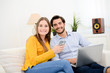 © W PRODUCTION - cheerful young couple on sofa at home websurfing and shopping online with laptop computer internet technology